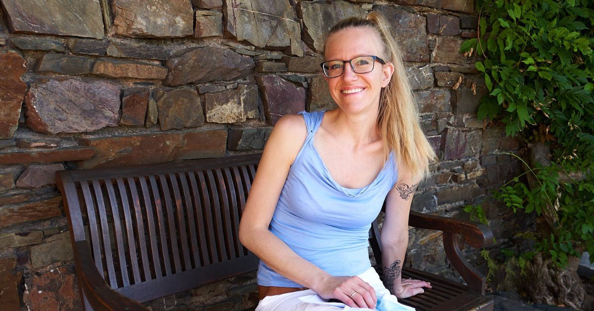 Lisa Jara on bench in front of stone wall for social media