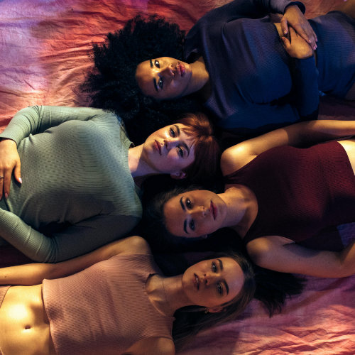 Image of four young people with different skin and hair colours, lying on their backs, dressed in underwear, heads together, looking confidently into the camera